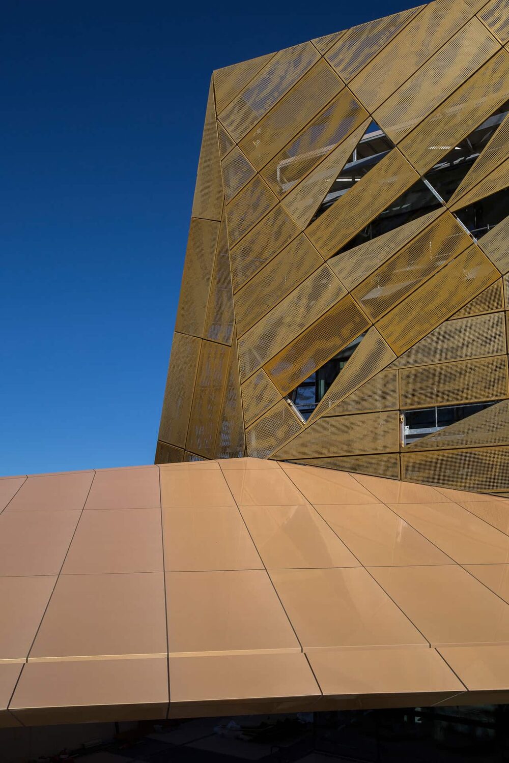 Perforated gold metal facade against a deep blue sky