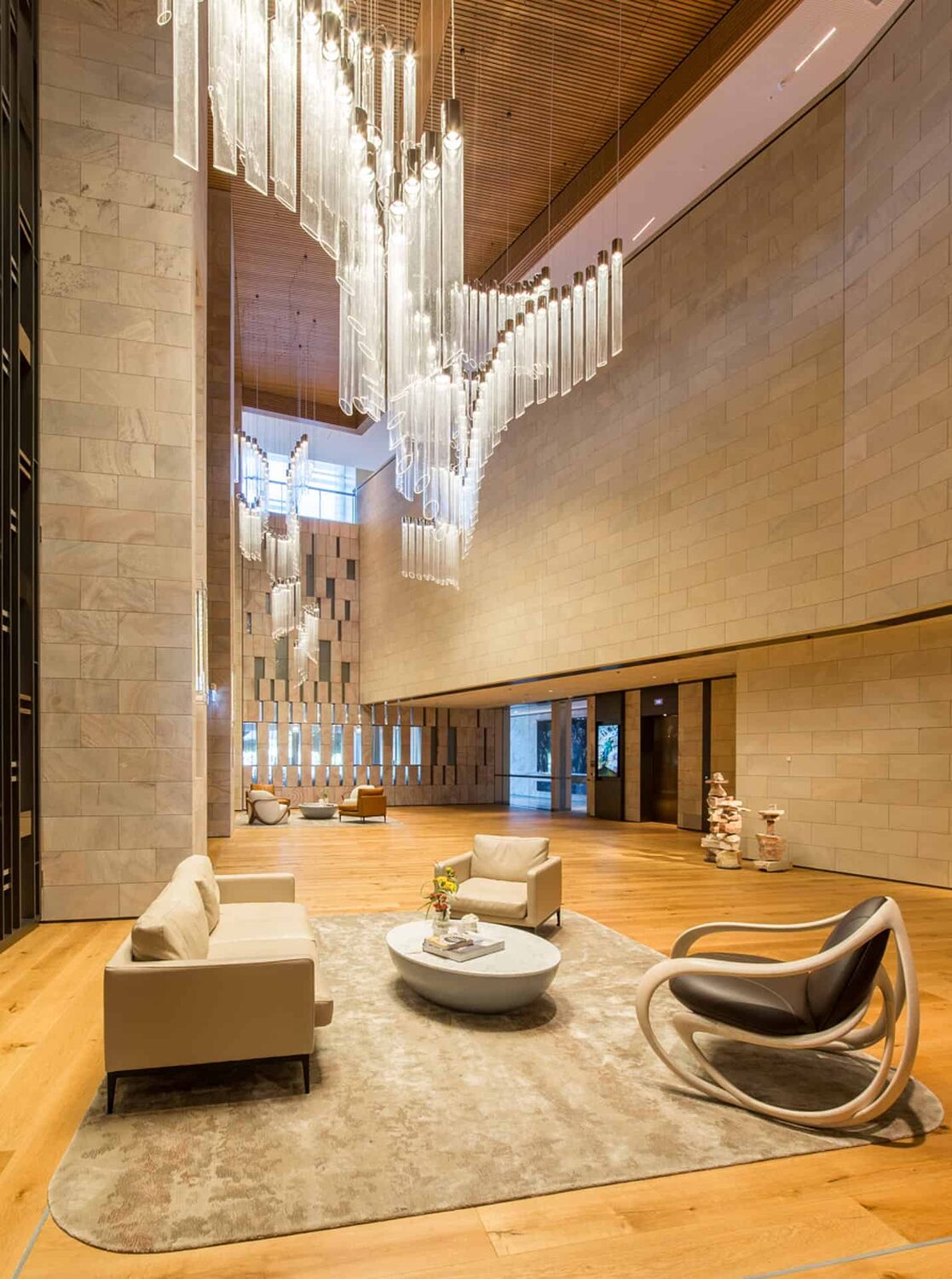 Double height hotel lobby with stone walls and a sculptural chandelier