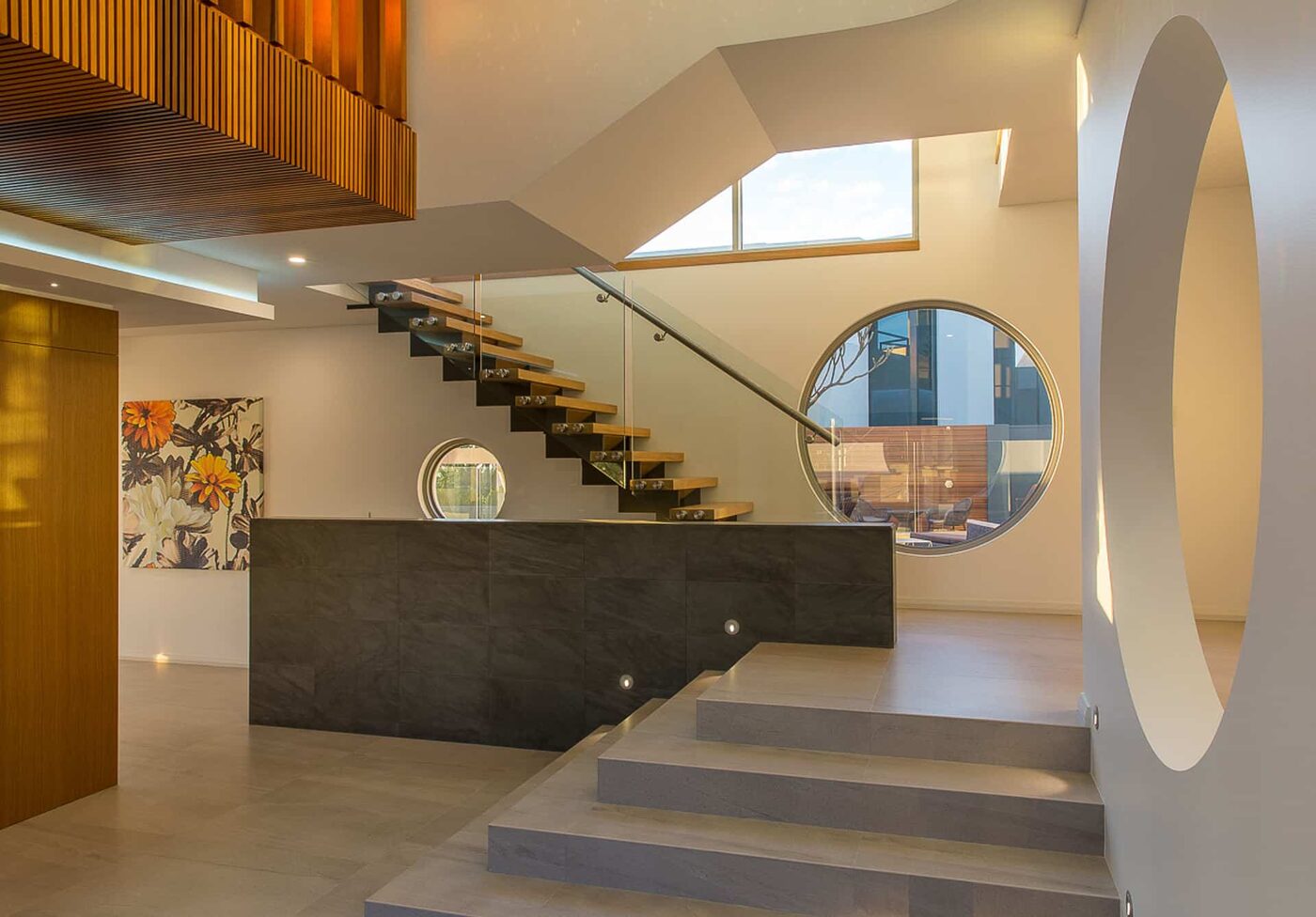 Residential interior with floating timber stair and circular window