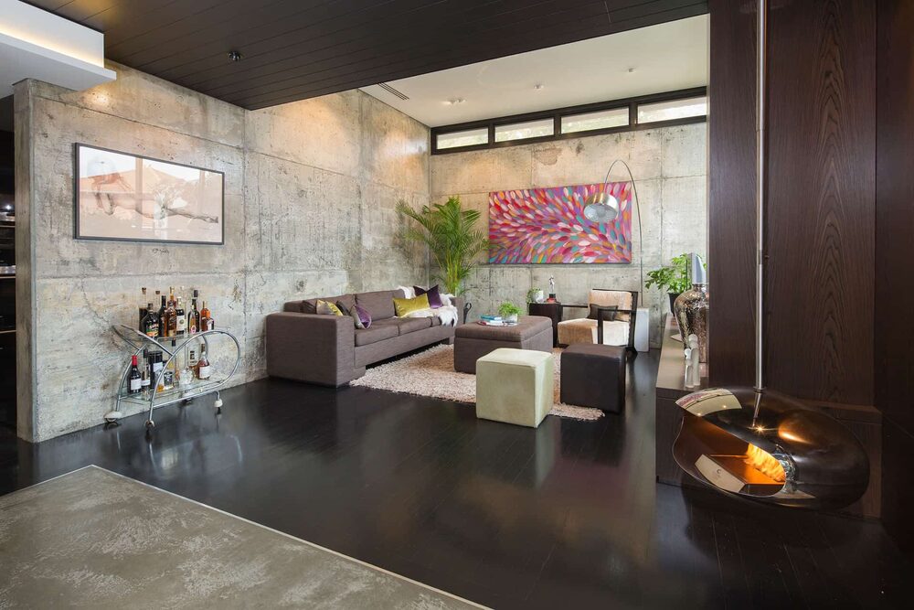 Living room with off-form concrete walls, artwork and a suspended fireplace